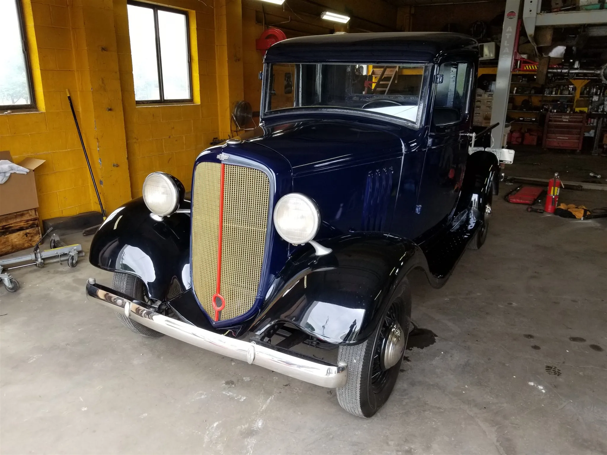 A dark blue 1935 Chevrolet truck inside the shop