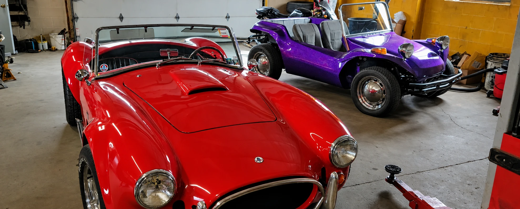 A red Cobra kit car and a purple VW dune buggy inside the shop